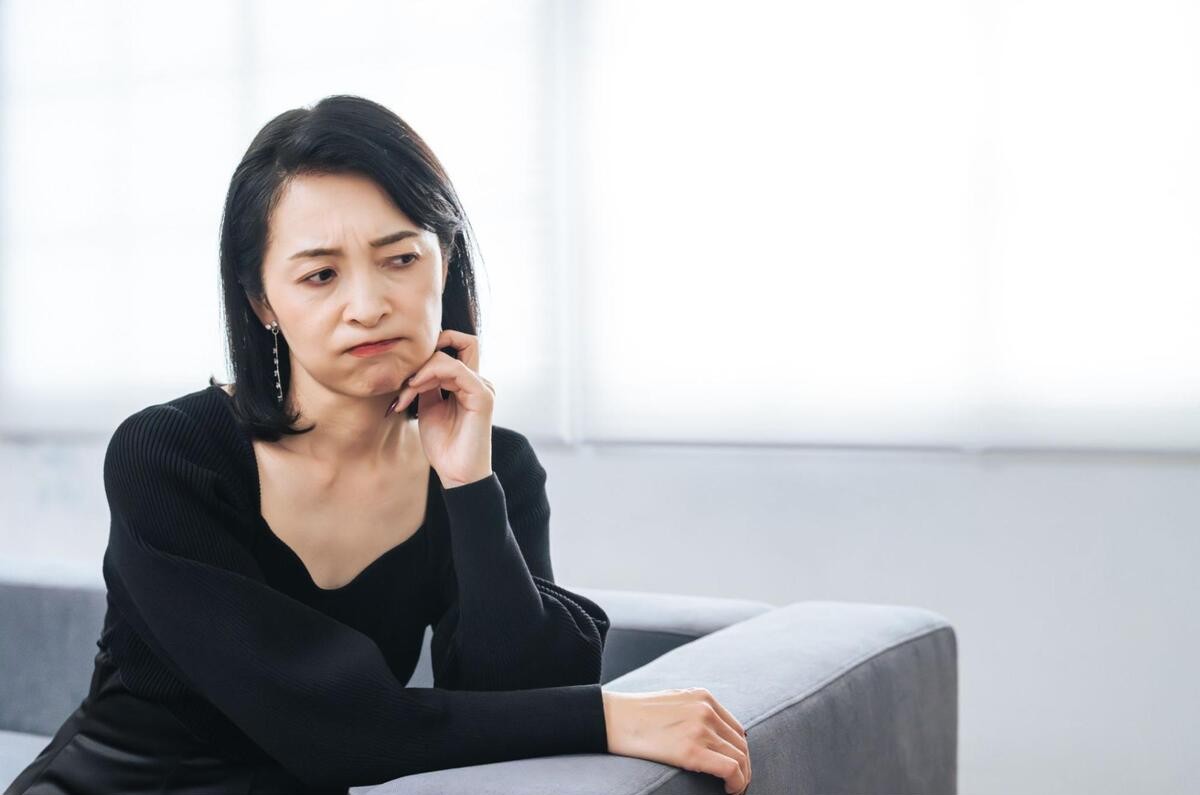 頬杖をついて顔のたるみに悩む様子の女性