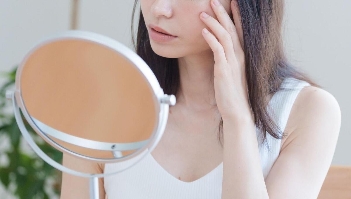 鏡を見て赤ら顔を確認する女性