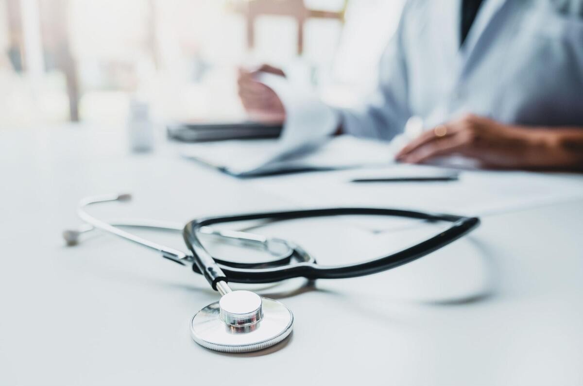 聴診器の置かれた机で資料を確認する美容皮膚科医