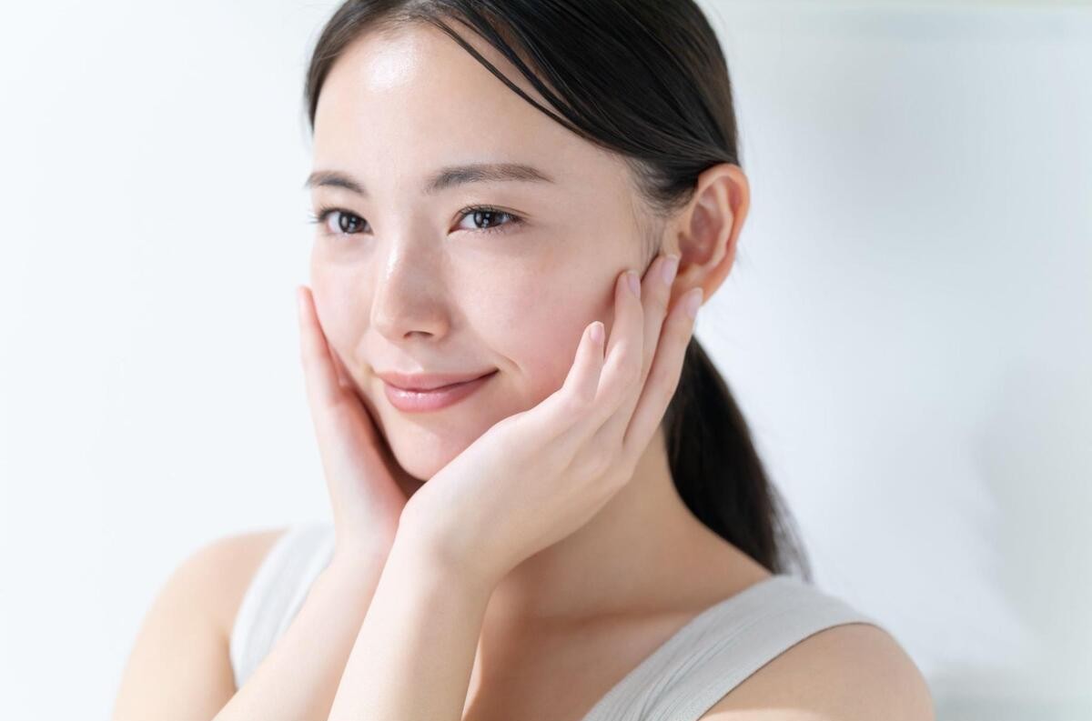 頬に手をあて、スキンケアをする女性