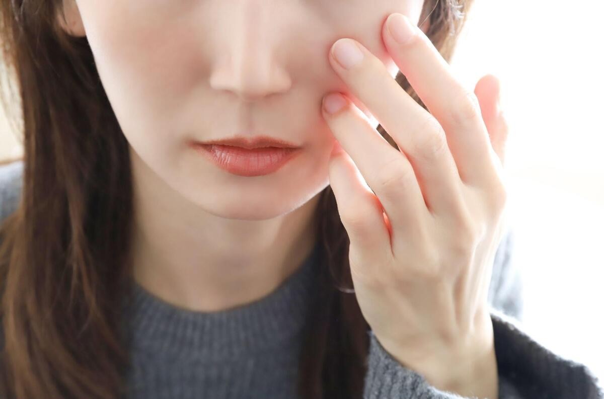 毛穴を気にして手で頬に触れている様子